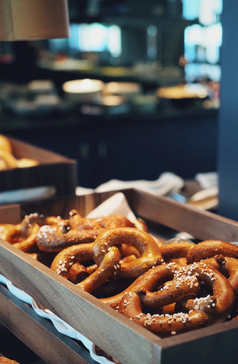 Nahaufnahme von frischen Brezeln im Holztablett, serviert im Buffetbereich des Jugend- und Familienhotel Augustin.